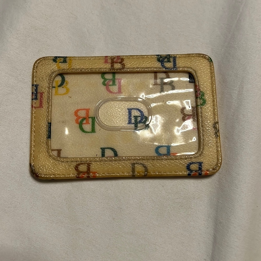 Dooney & Bourke card holder in beige with colorful logo print.